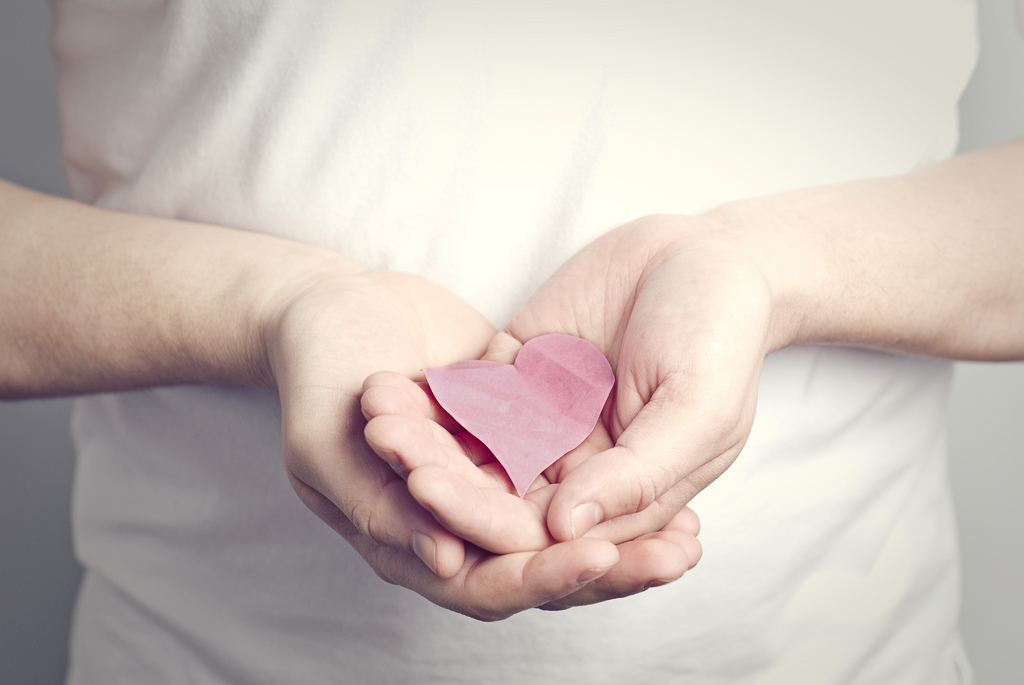 Corazón de papel sujeto por dos manos